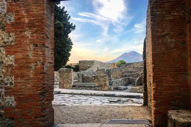 Vesuvius framed between two brick pillars in Pompeii, with ruins below