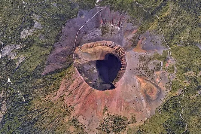 Aerial view straight down into the crater of Vesuvius, ringed by red and grey slopes