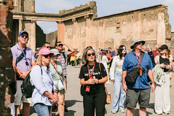 A tour group in sun hats listening to a guide among the ruins of Pompeii